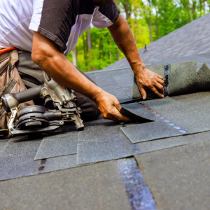 Person laying shingles down on a roof